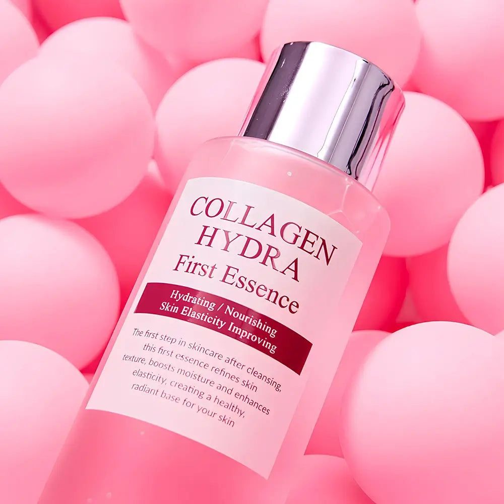 Flasche mit "Collagen Hydra First Essence" Etikett, umgeben von rosa Kugeln.