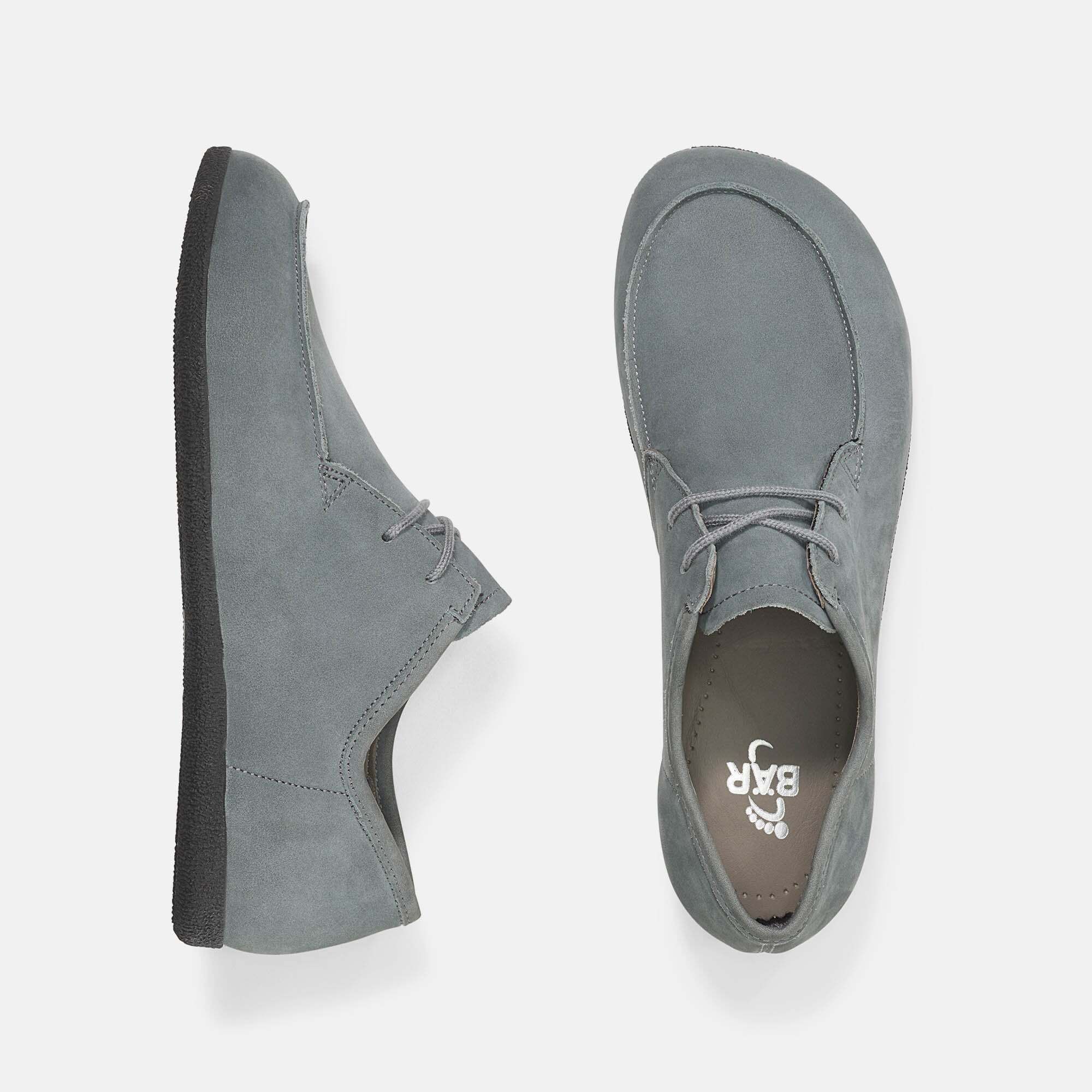 Graue Schnürschuhe. Obermaterial aus Wildleder. Runde Schuhspitze. Schwarze Sohle. Hellgraue Schnürsenkel. Schuhsohle mit Logo.