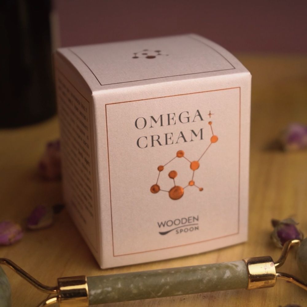 Rosa Kartonverpackung mit Aufschrift OMEGA+ CREAM und Wooden Spoon. Geometrische Illustration. Jade-Roller.