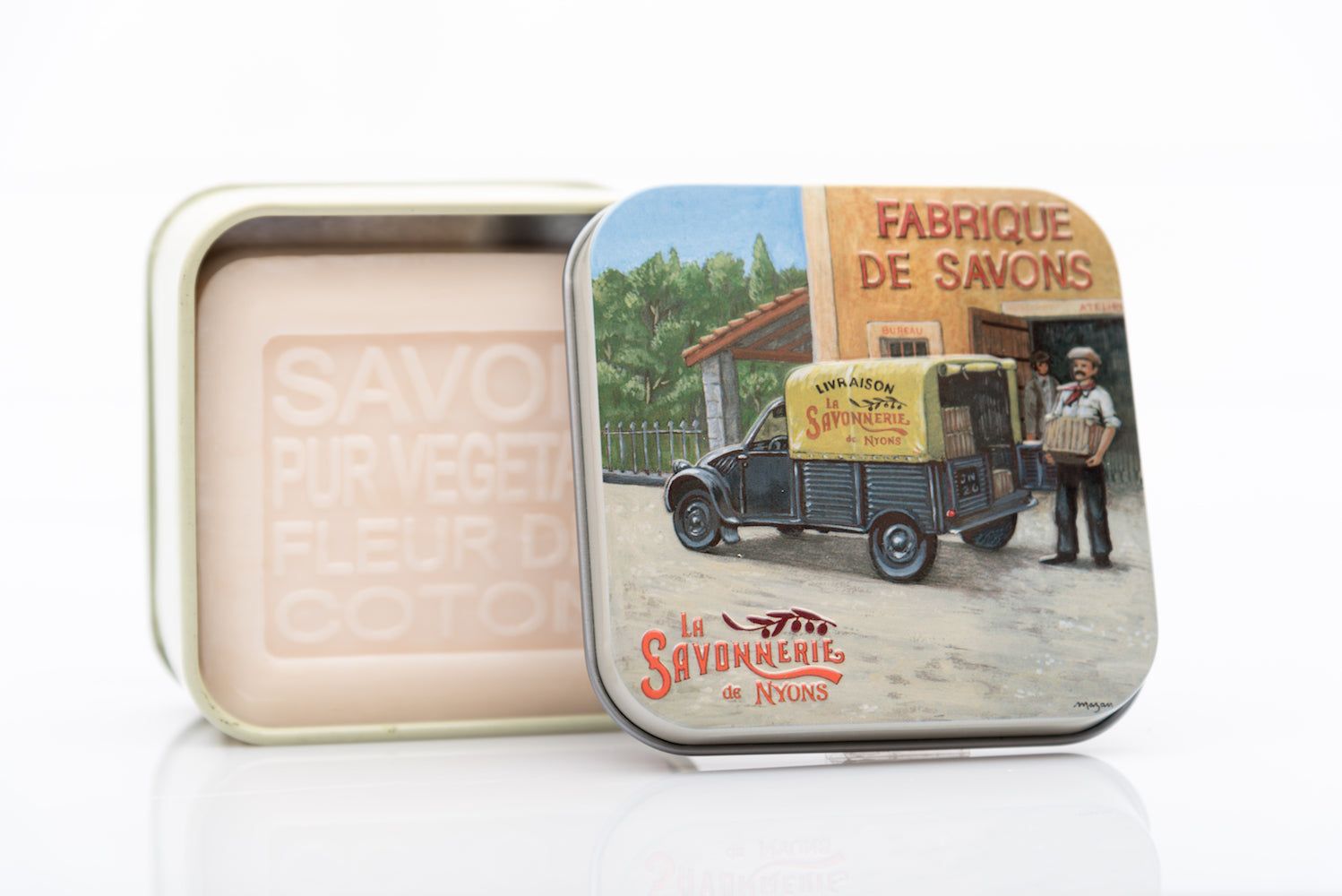 Geöffnete Metallbox mit Seife. Box mit Illustration: Fabrique de Savons, LKW, Mann. Seife mit Prägung: Savon Pur Végétal.
