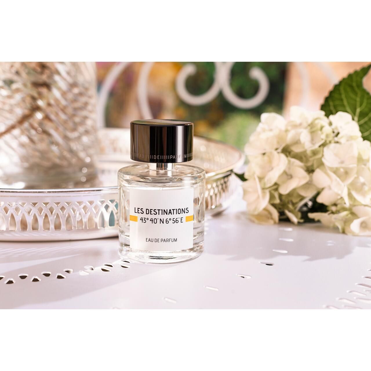 Parfümflakon auf Tablett. Aufschrift: Les Destinations, Eau de Parfum. Schwarzer Deckel, transparente Flasche.