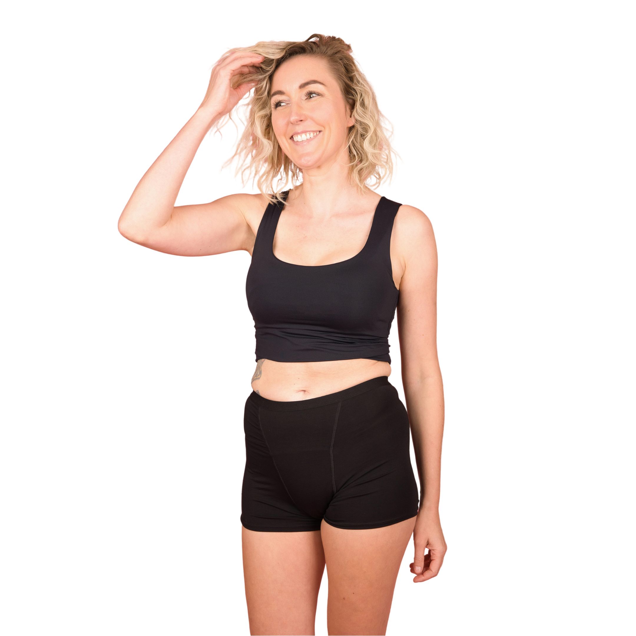 Schwarze Boxershorts. Frau trägt ein schwarzes Top und Shorts. Blick nach rechts. Helle Haut, blonde Haare.