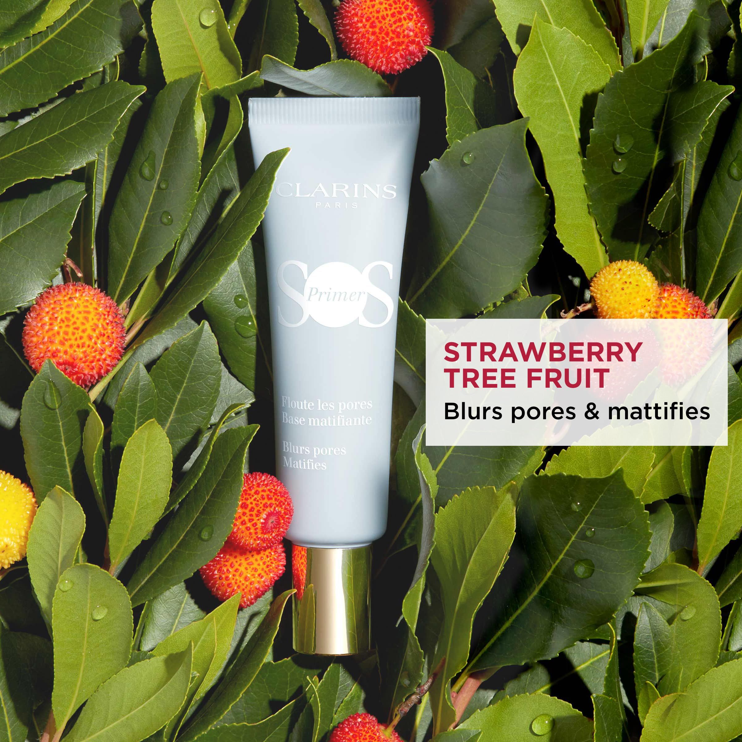 Clarins SOS Primer, umgeben von Blättern und Früchten. Text: Strawberry Tree Fruit, Blurs pores & mattifies.