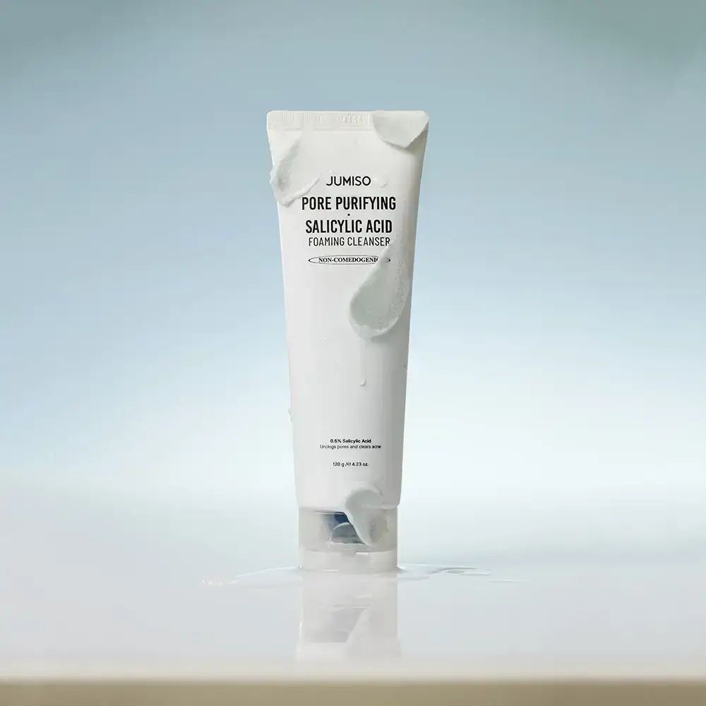 Weiße Tube mit Schaum. Text: JUMISO Pore Purifying Salicylic Acid Foaming Cleanser. Auf blauem Hintergrund.
