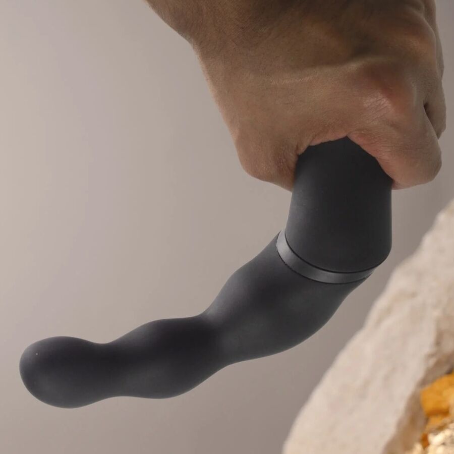 Hand hält schwarzen Vibrator. Gebogene Form mit abgerundeten Enden und einem Ring.