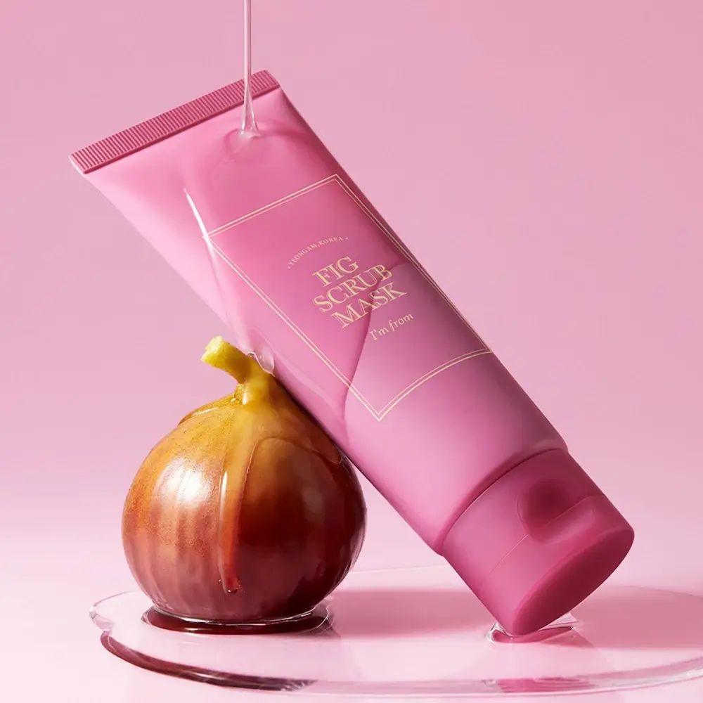 Rosa Tube mit goldfarbenem Aufdruck, neben einer Feige. Aufschrift: FIG SCRUB MASK, I'M FROM. Produktverpackung.