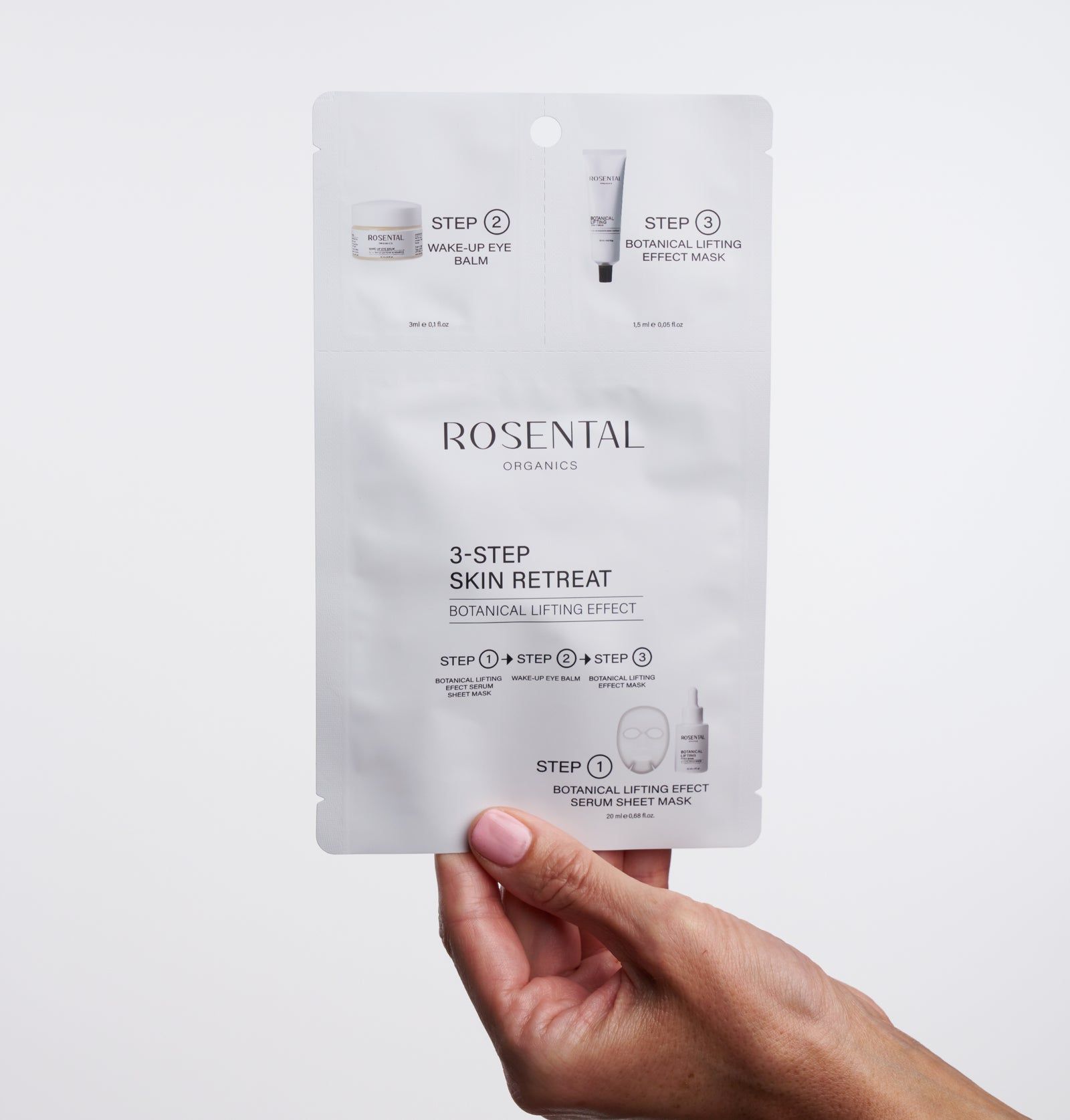 Hand hält eine weiße Verpackung mit Produktabbildungen und Text. "Rosental Organics 3-Step Skin Retreat" ist sichtbar.