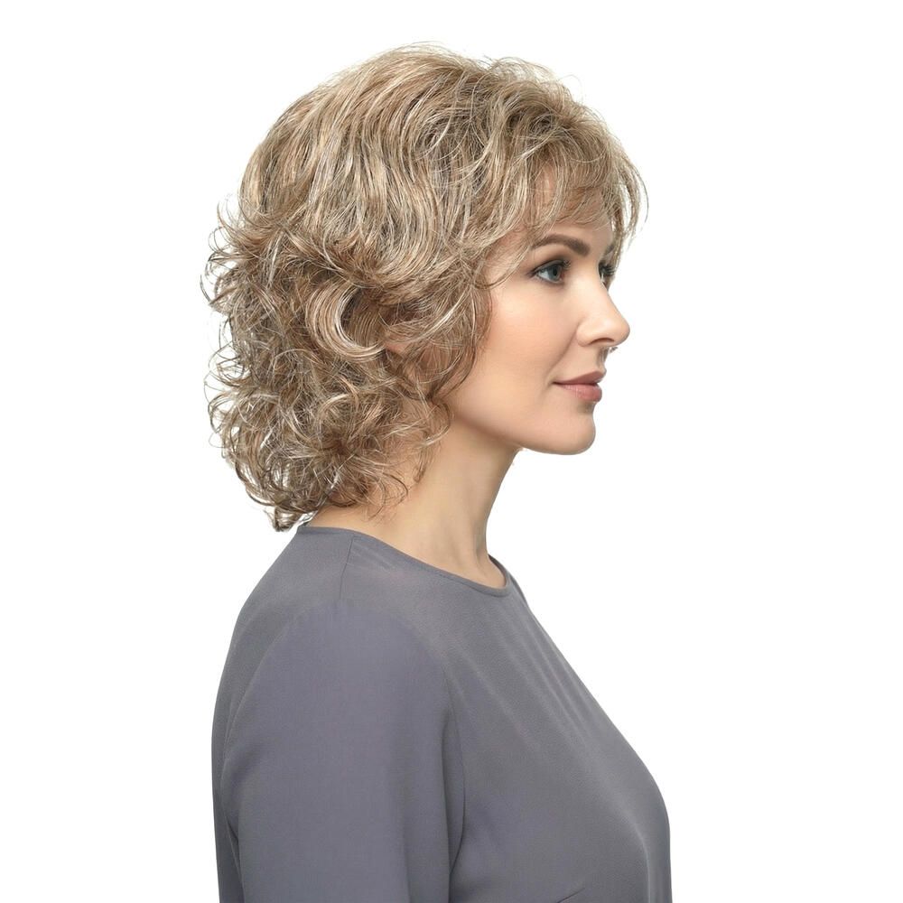 Frau mit Perücke. Kurze, wellige Haare in Blond- und Brauntönen. Seitenansicht.