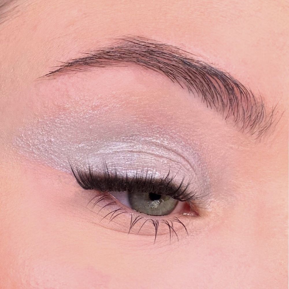 Auge mit silberfarbenem Lidschatten. Wimpern und Augenbrauen sichtbar. Hautton rosa.