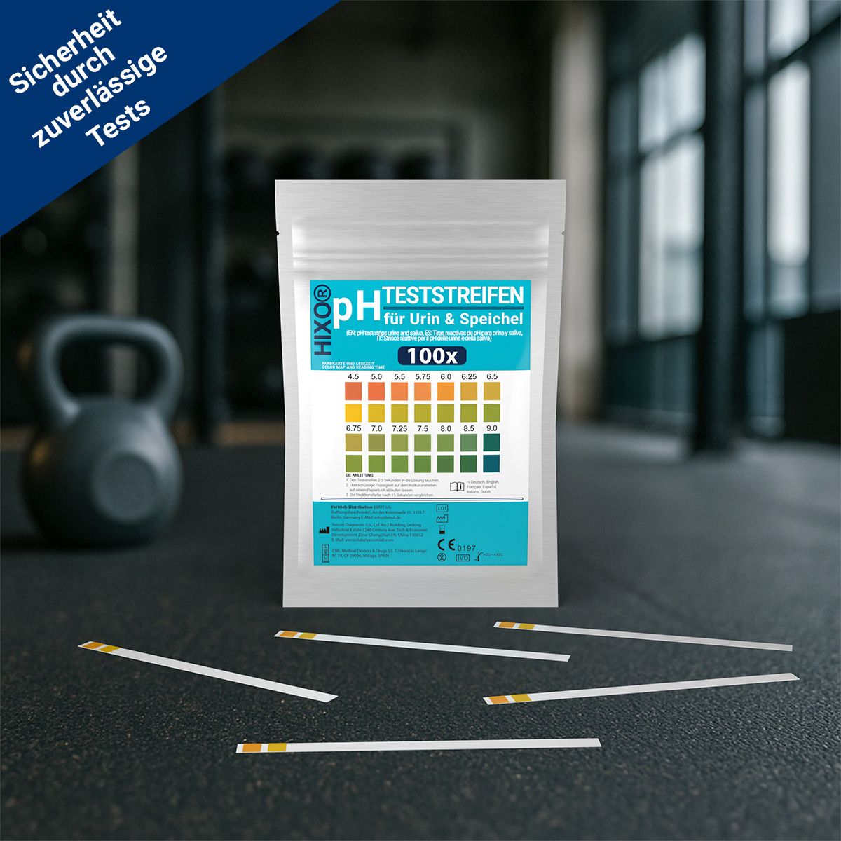 Produktverpackung mit pH-Teststreifen. Text: pH Teststreifen für Urin & Speichel, 100x. Streifen liegen daneben. Hintergrund: Fitnessstudio mit Hantel.