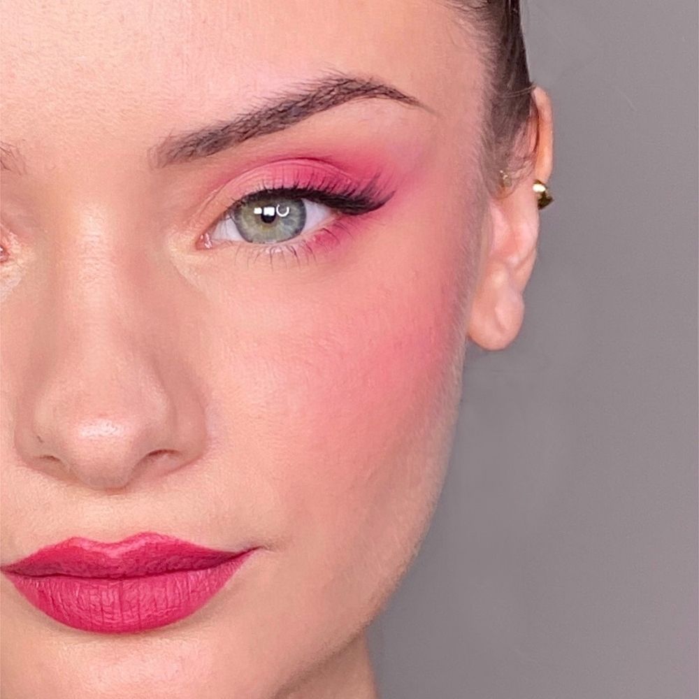 Nahaufnahme eines Gesichts mit rosa Make-up. Rosa Lidschatten, Rouge und Lippenstift. Grünes Auge.