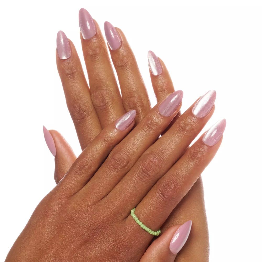 Hände mit aufgesetzten künstlichen Nägeln. Rosa Nägel mit Glanzeffekt. Ein grüner Ring am Finger.