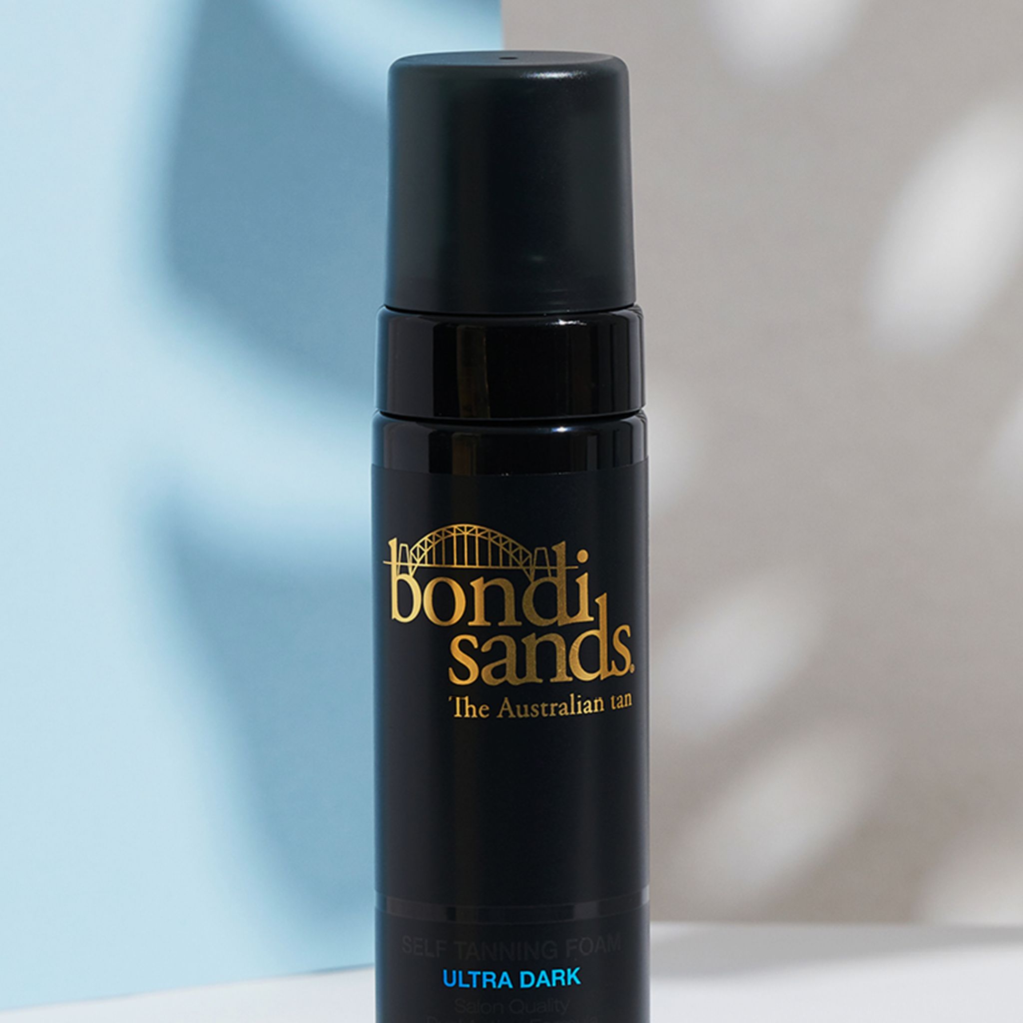 Gros plan d'un flacon noir avec logo Bondi Sands et texte 'Ultra Dark'. Contient de la mousse autobronzante.