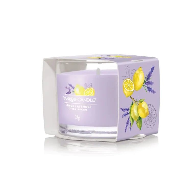 Duftkerze im Glas in Verpackung. Fliederfarbenes Wachs mit Aufdruck von Zitrone und Lavendel. Beschriftung: Lemon Lavender, Citron Lavande, 37g.