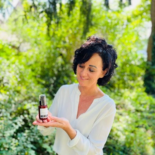 Frau hält Produktflasche. OXY8 Deep Hydrating Night Cream. Braune Flasche mit Pumpe. Zertifiziertes Bio-Produkt.