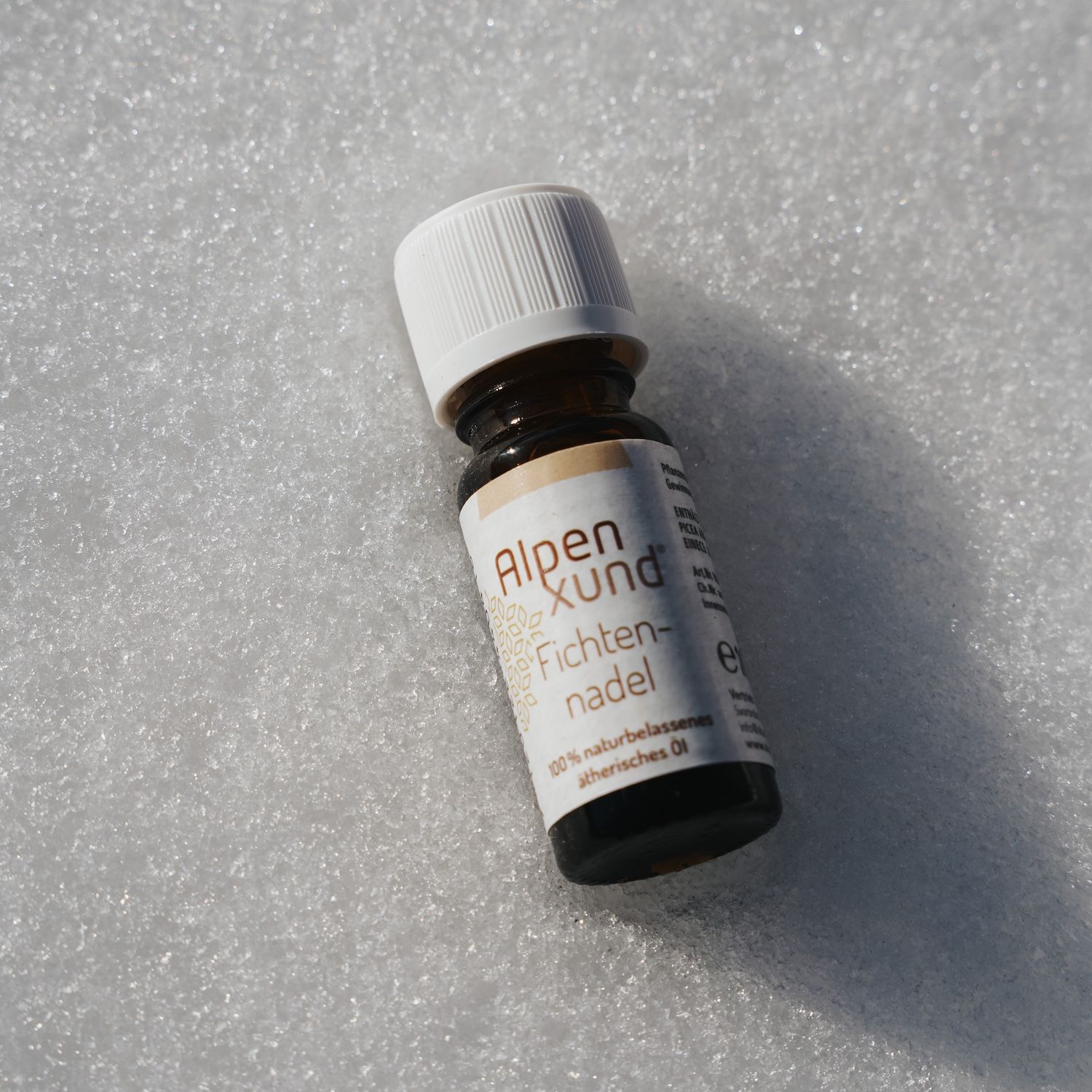 Braune Glasflasche mit weißem Deckel. Etikett mit AlpenXund und Fichtennadel. Auf weißem Untergrund.