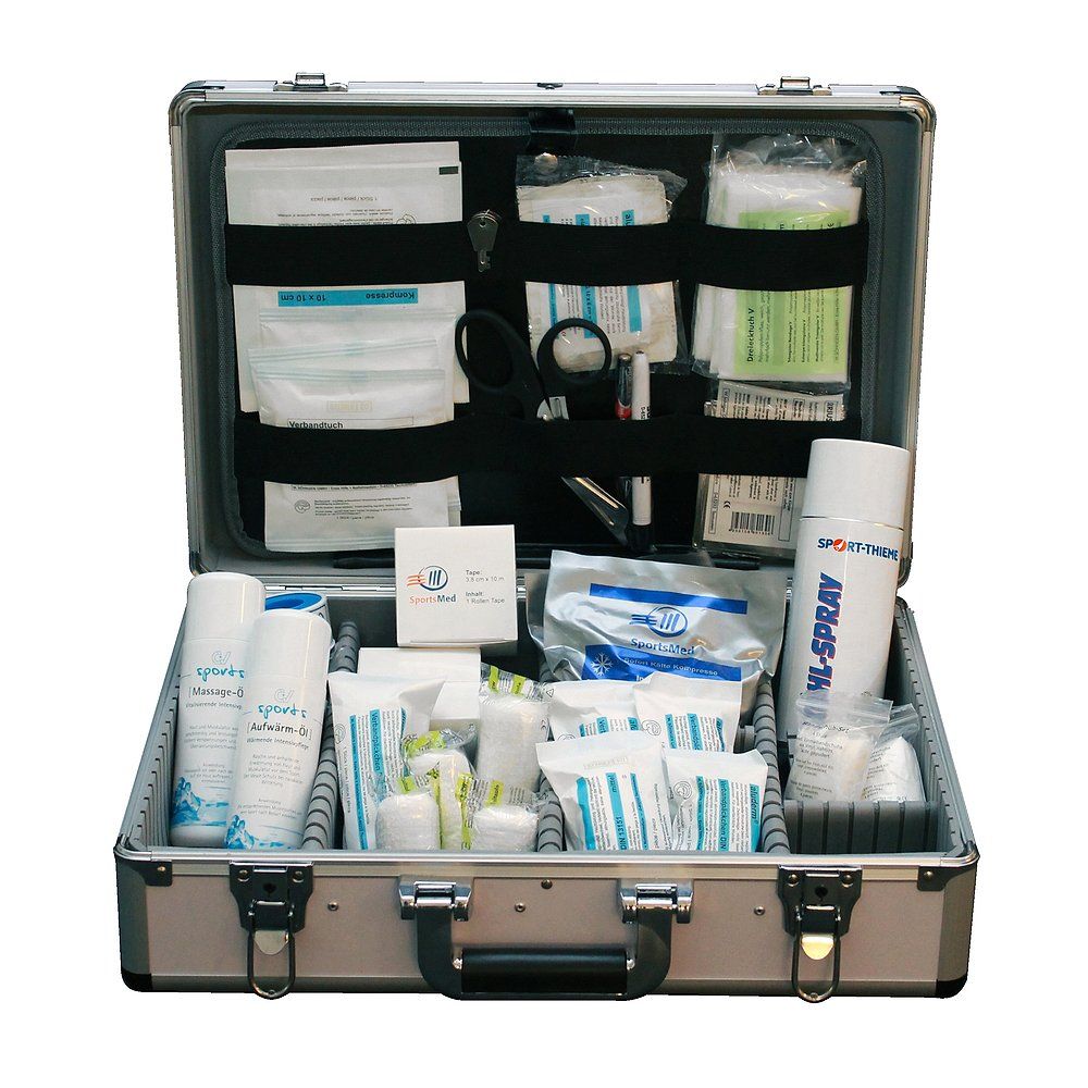 Sanitätskoffer, geöffnet. Silberfarbenes Gehäuse mit medizinischen Artikeln. Enthält Verbandsmaterial, Sprays und weitere medizinische Produkte.