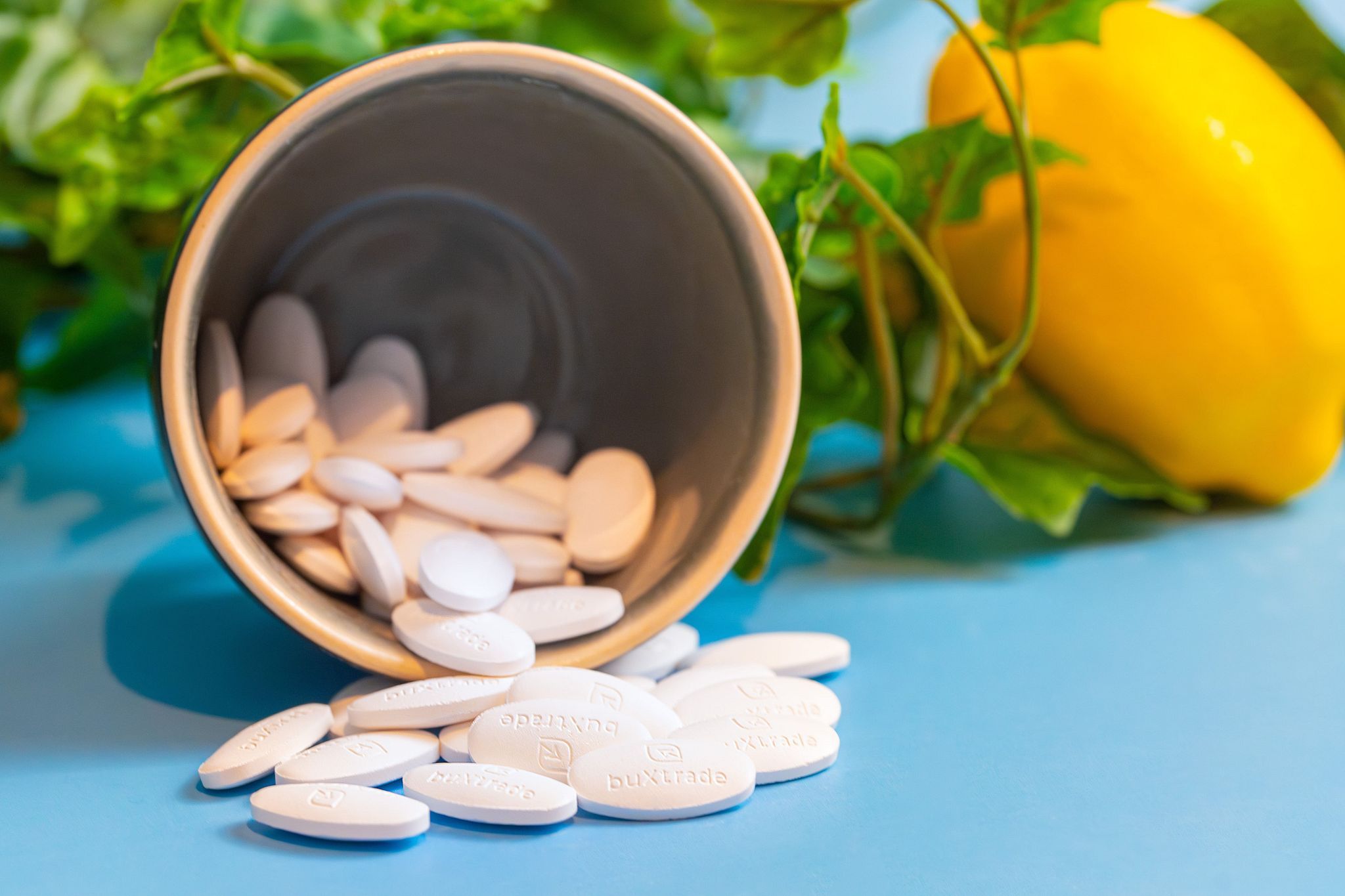 Tabletten in einem Becher, daneben Zitrone und Blätter. Tabletten mit Prägung.