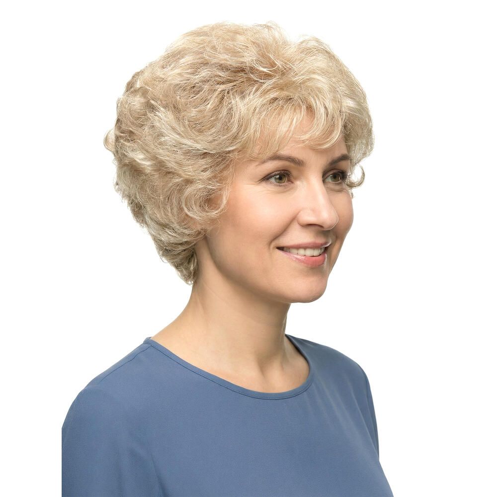 Blond gelockte Perücke. Nahaufnahme einer lächelnden Frau mit blauem Oberteil. Kurze, wellige Frisur.