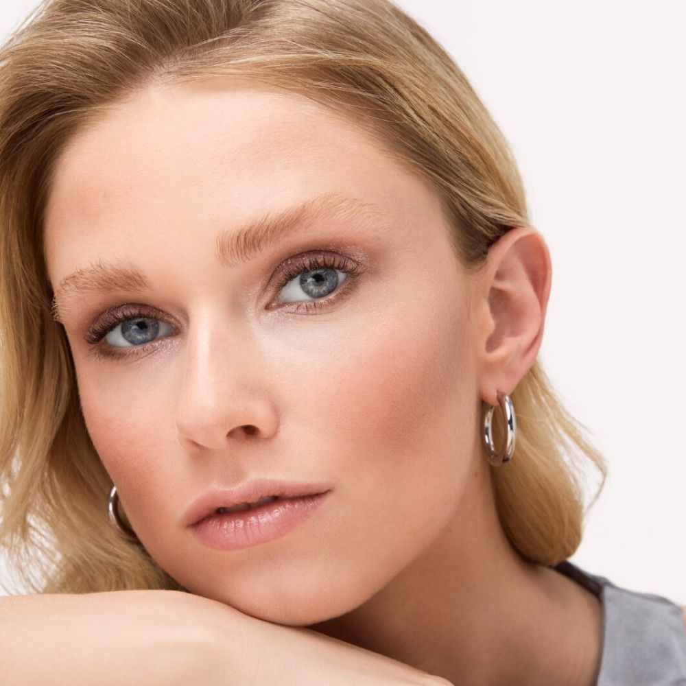 Porträt einer Frau mit blonden Haaren und blauen Augen. Sie trägt Lidschatten.