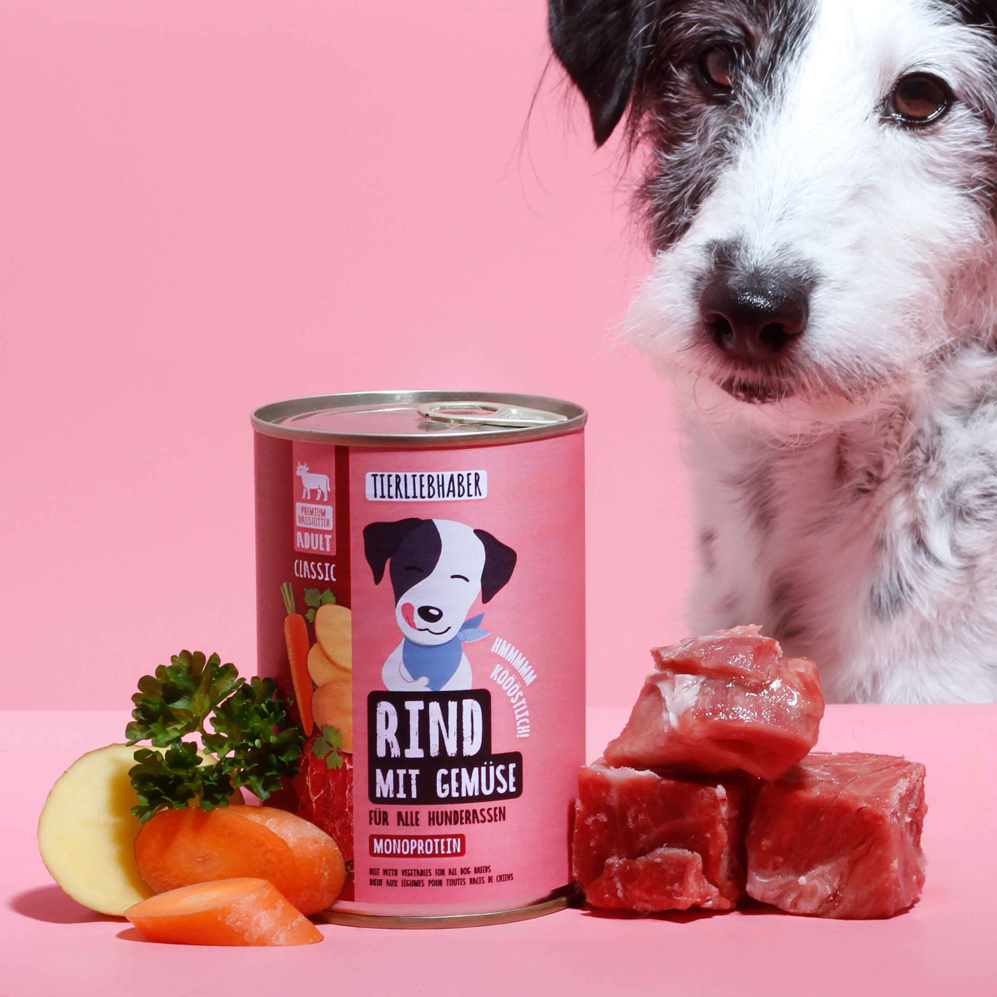 Rosa Dose mit Aufschrift "Tierliebhaber Rind mit Gemüse". Daneben Fleischstücke, Gemüse und ein Hund.