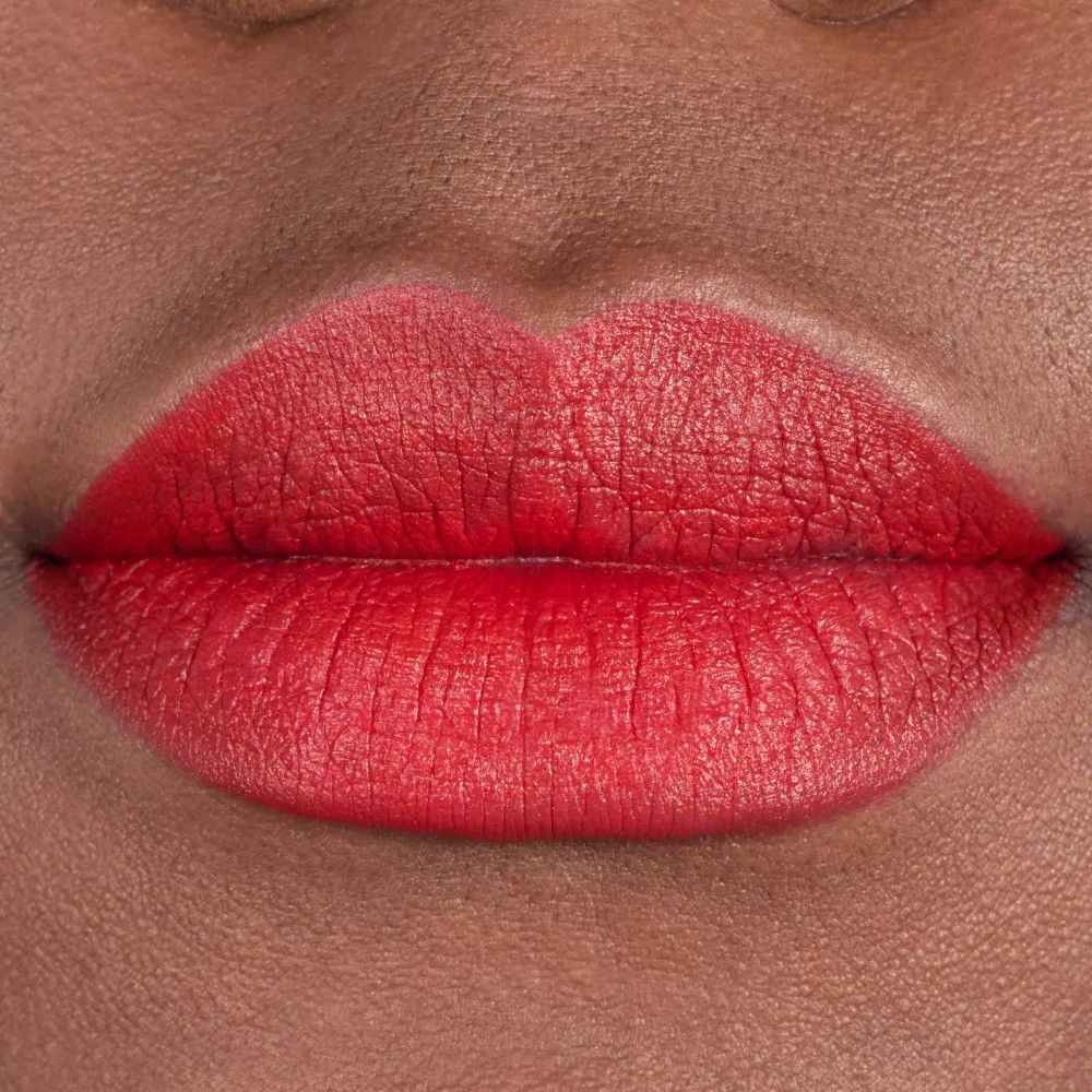 Nahaufnahme von Lippen, die mit rotem Lippenstift bemalt sind. Die Lippen sind voll und glänzend. Weiße Zähne sind sichtbar.