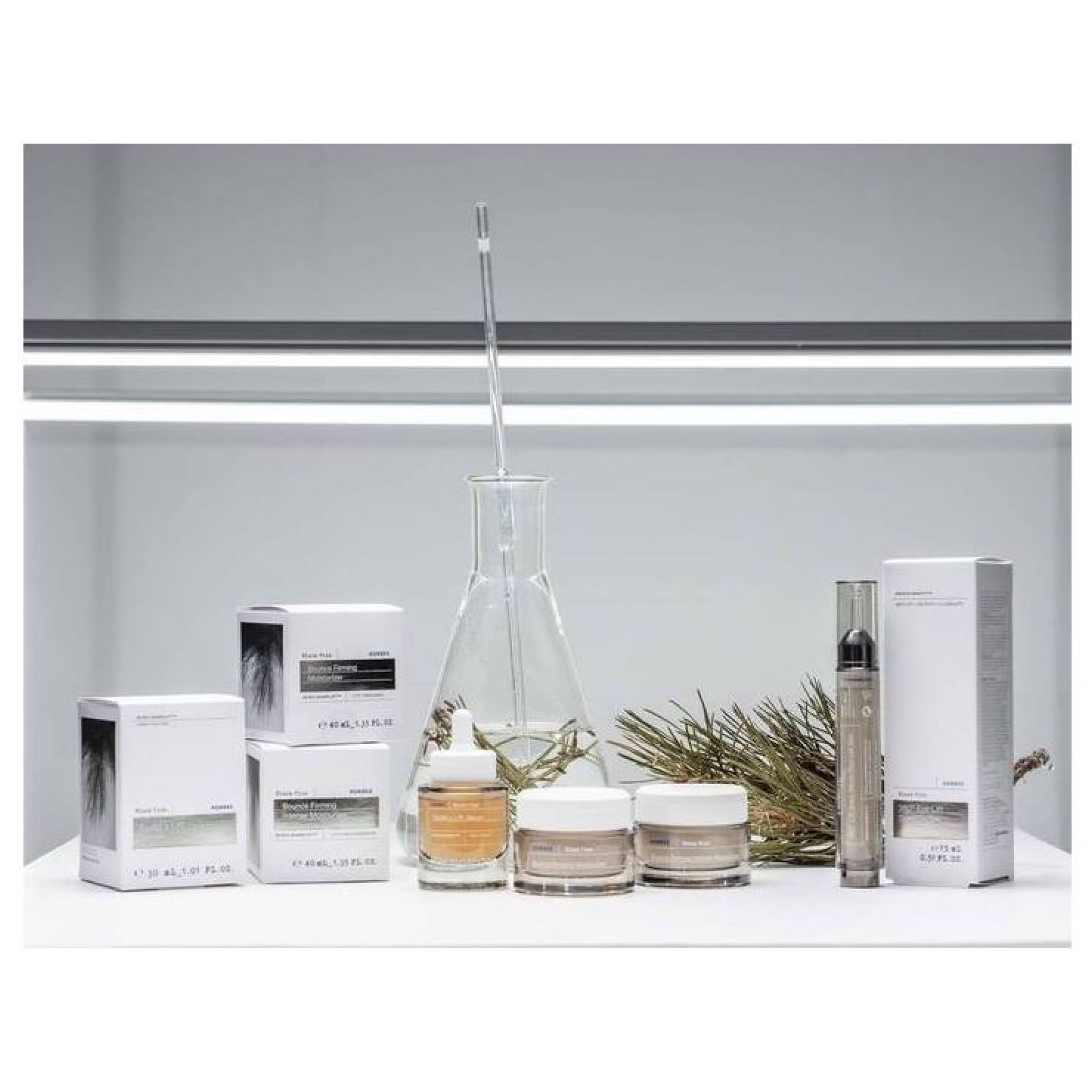 Produktpräsentation mit KORRES Black Pine Produkten und Laborutensilien.