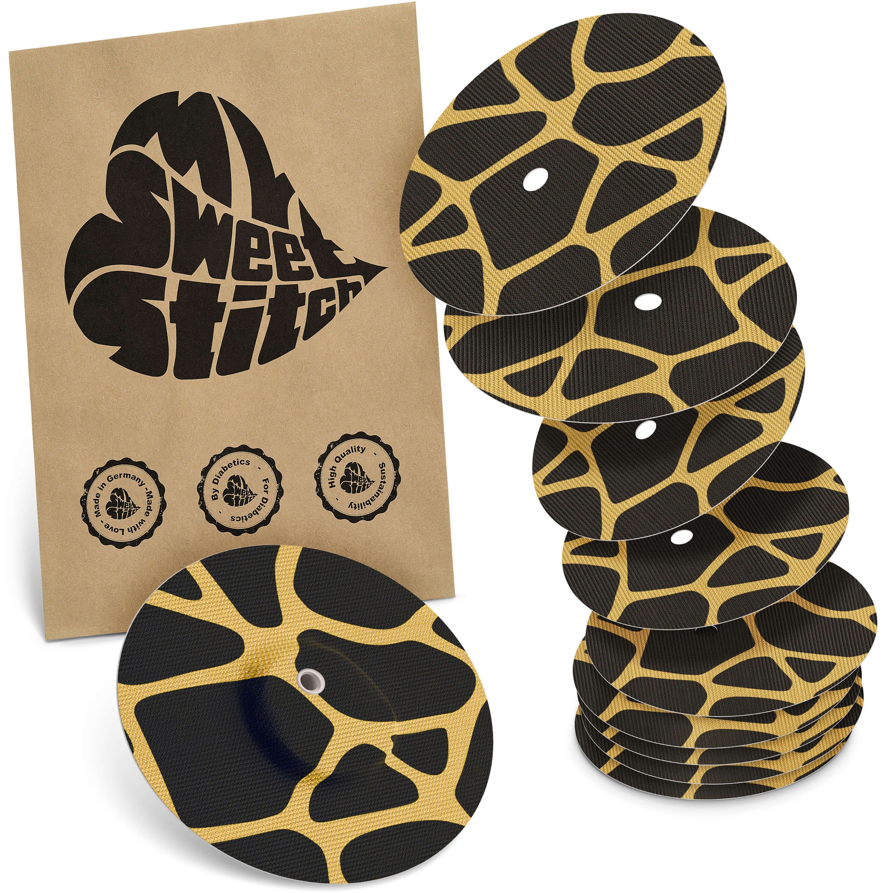 Fixierpflaster mit Giraffenmuster. Mehrere ovale Pflaster mit Loch, neben einer braunen Verpackung mit Logo.
