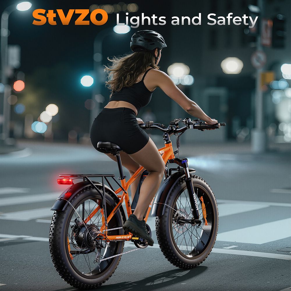 Person fährt auf einem orangefarbenen VARUN E-Mountainbike bei Nacht. StVZO-Beleuchtung. Schwarze Kleidung, Helm.