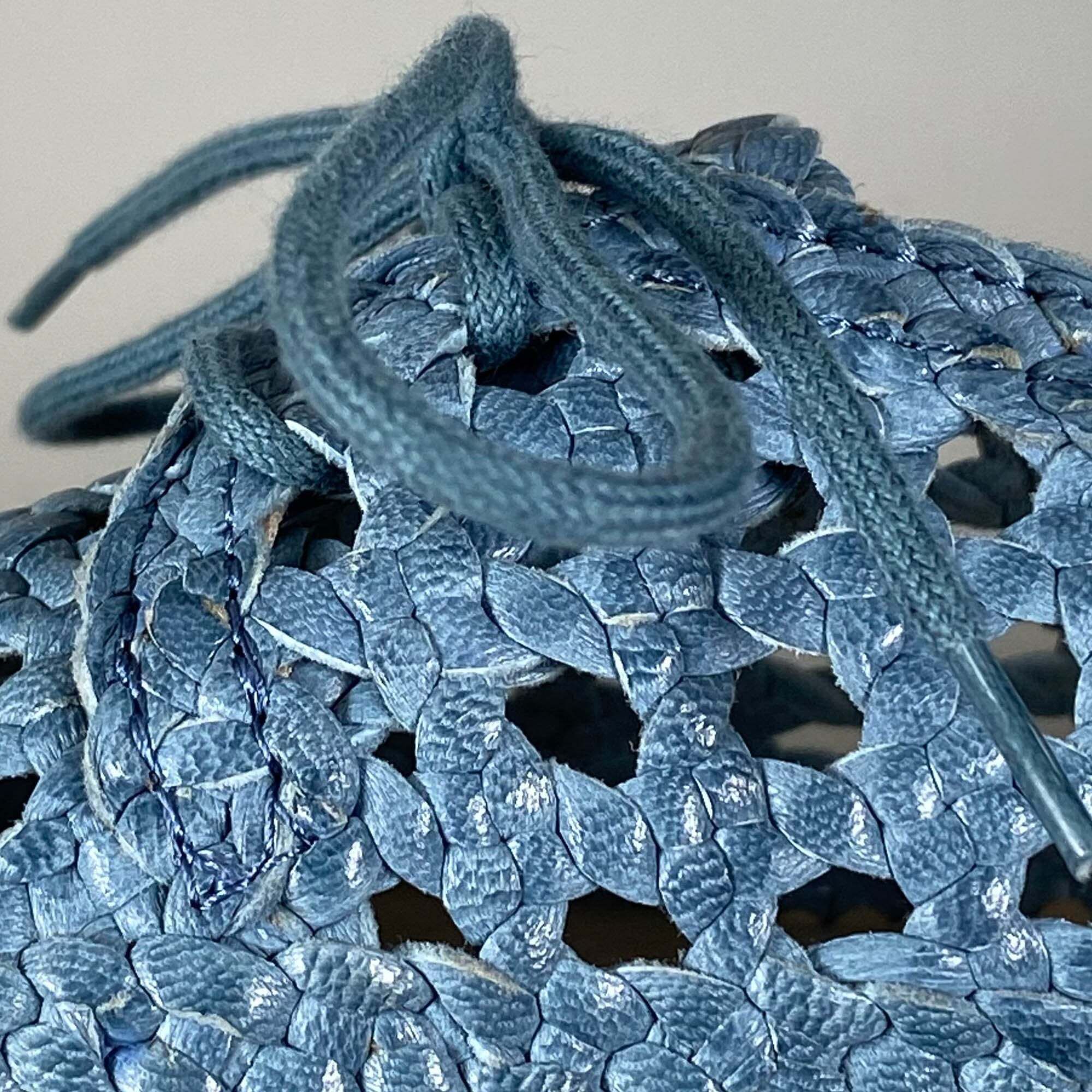 Detailansicht einer blauen, geflochtenen Schuhkonstruktion mit Schnürsenkeln.
