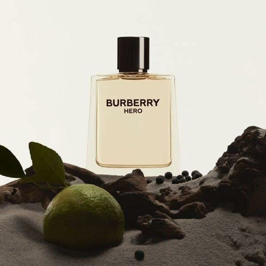 Burberry Hero E.d.T. Nat. Spray. Flakon auf Sand und Holz. Aufschrift: BURBERRY HERO. Limette und Beeren.