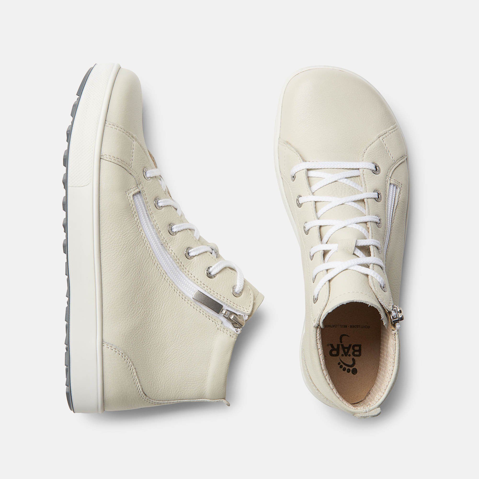 Zwei beige Stiefeletten. Schnürsenkel und Reißverschluss. Weiße Sohle. Breite Passform. Innen: BÄR Logo.