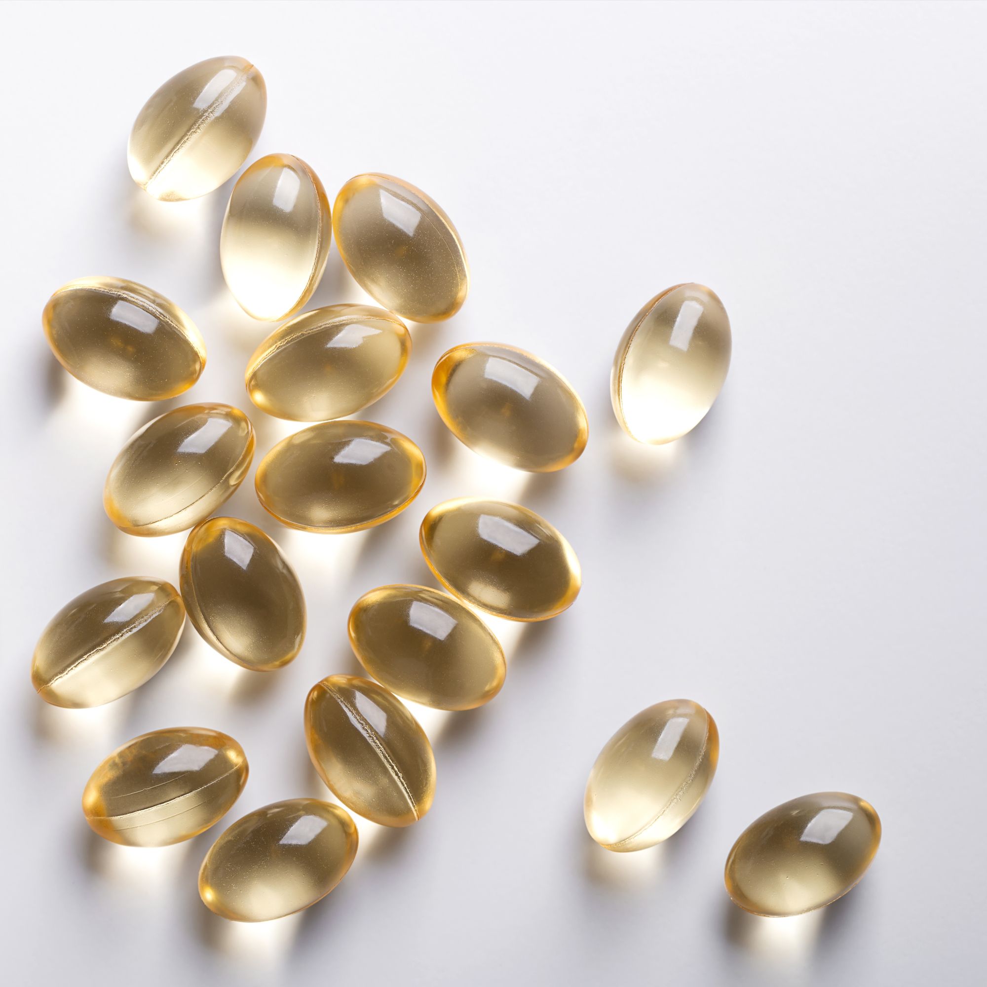 Mehrere ovale, gelbliche Kapseln auf weißem Hintergrund. Die Kapseln sind durchscheinend und liegen verstreut.