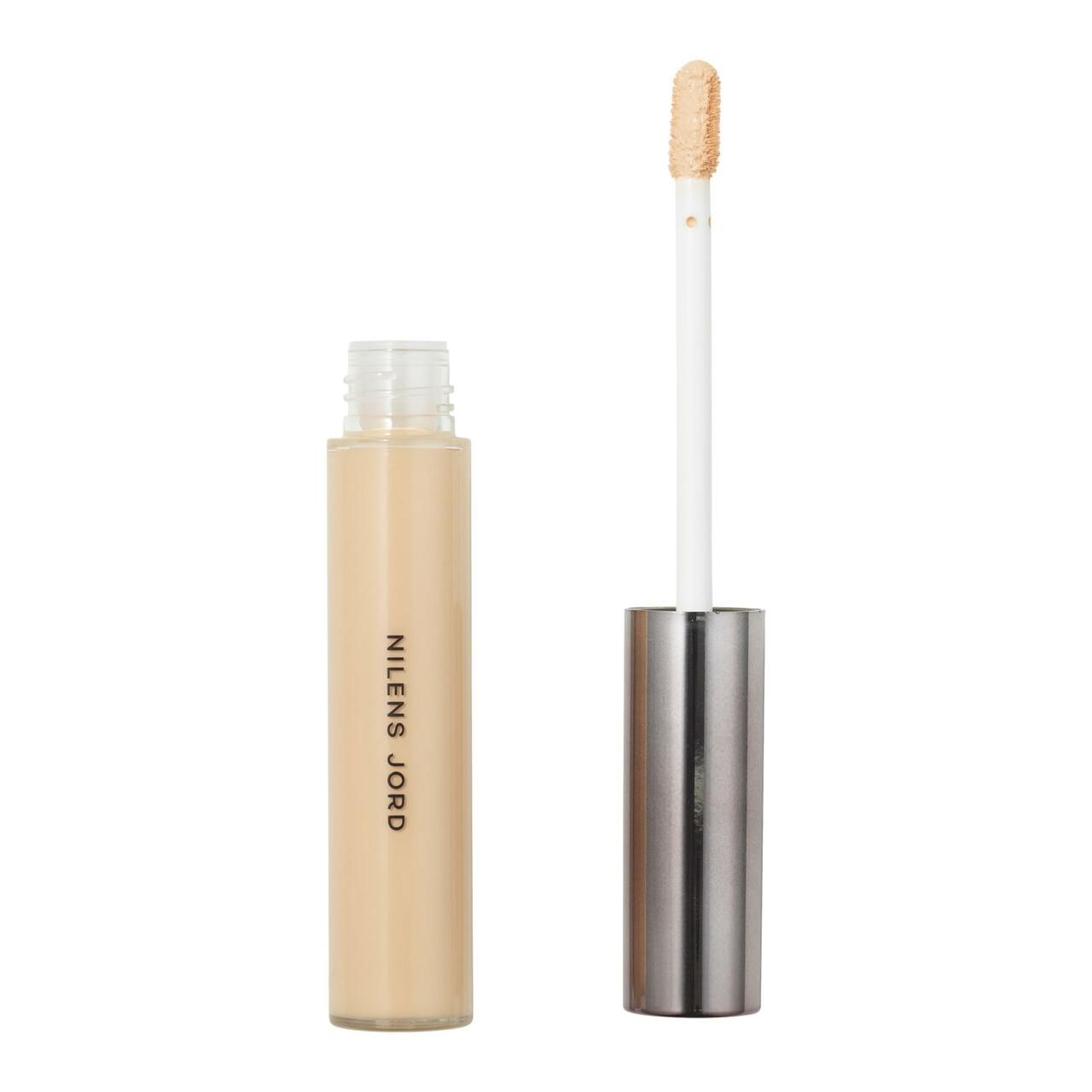Beige Concealer-Tube mit geöffnetem Deckel und Applikator. Aufschrift: Nilens Jord. Applikator mit Produkt.