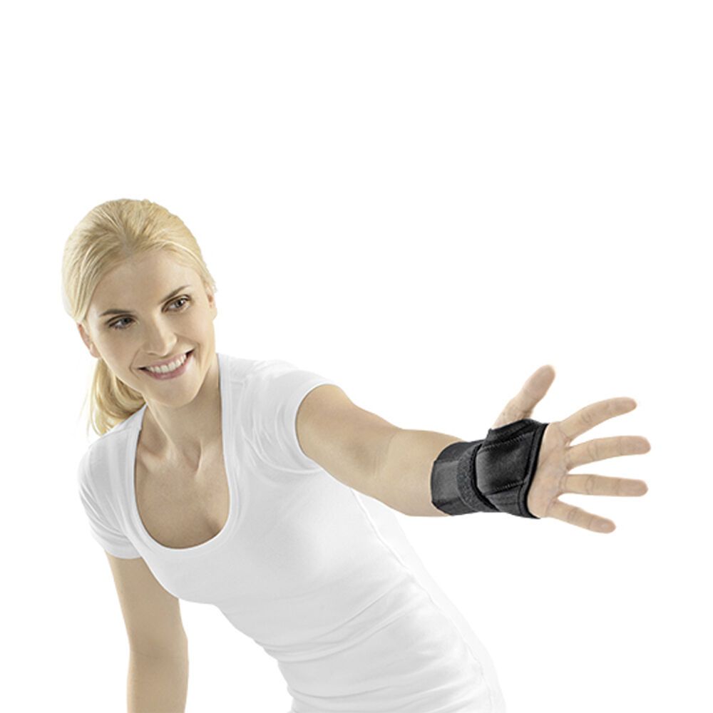 Frau mit schwarzer Handgelenkstütze am linken Handgelenk. Klettverschlüsse und schwarzes Material. Arm in Richtung Kamera ausgestreckt.