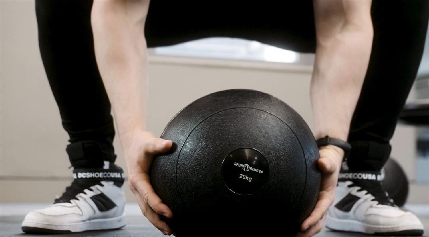 Person hält einen schwarzen Slamball mit der Aufschrift "20kg".