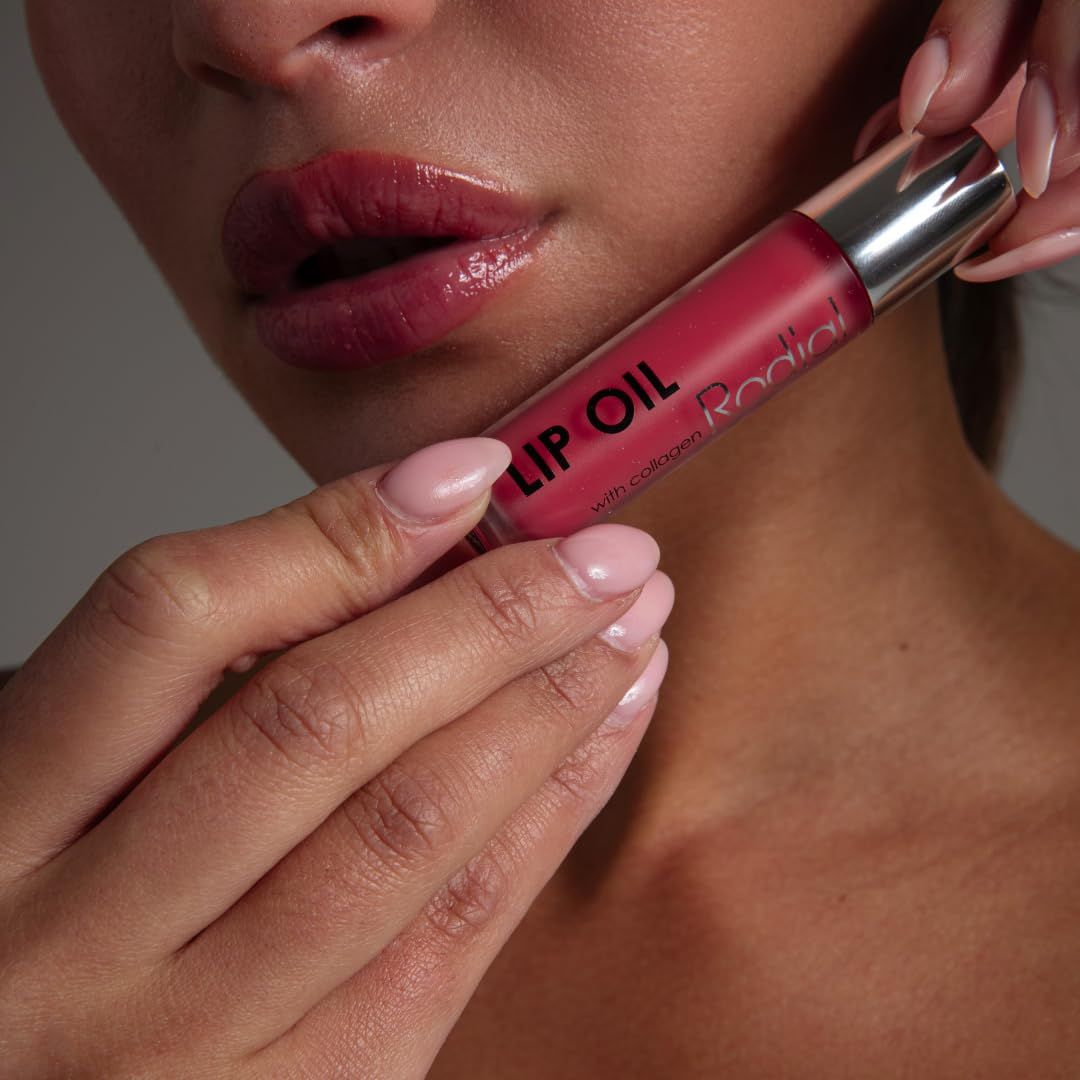 Hände halten Lippenöl-Flakon. Aufschrift: LIP OIL, Rodial. Lippen glänzend. Rosa Nagellack.