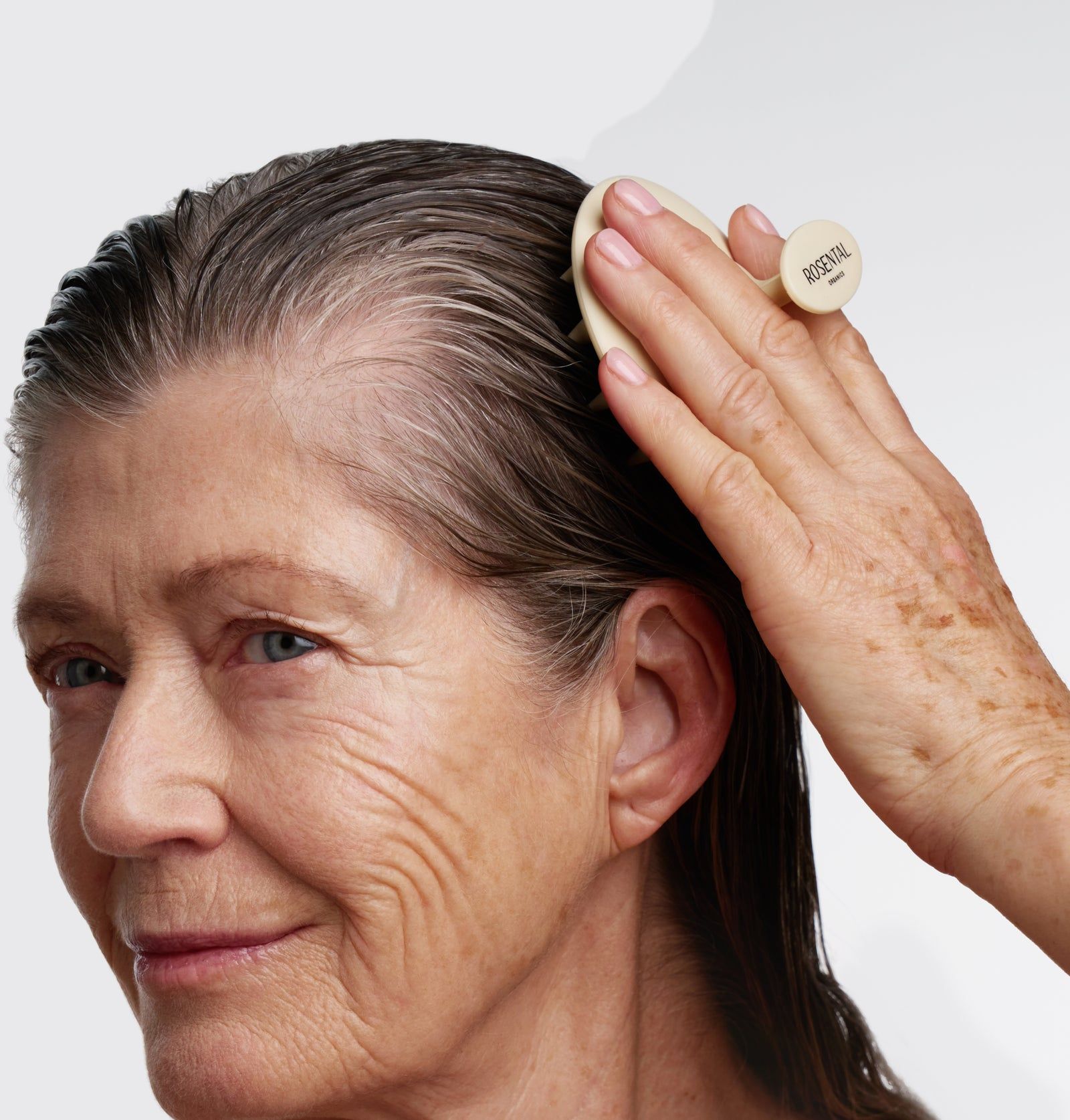 Hautbürste in Anwendung. Beige Bürste mit Griff, auf Kopfhaut angewendet. Auf dem Griff steht "ROSENTAL".