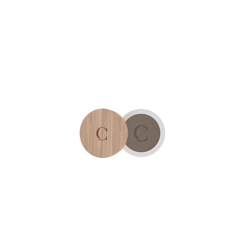 Runder Lidschattenbehälter, geöffnet. Deckel aus Holz mit 'C'. Lidschatten in Braun. Aufschrift 'C'.