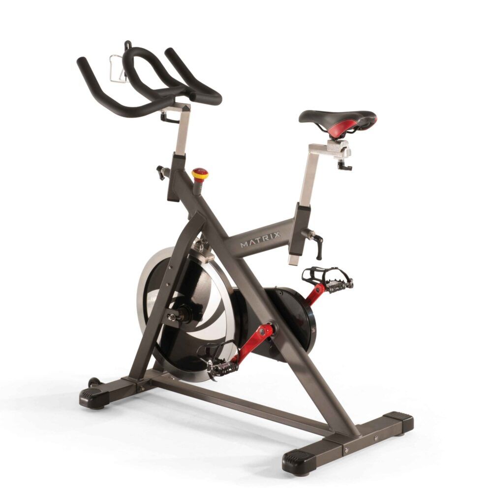 Indoor Cycle mit Lenker, Sattel und Pedalen. Grauer Rahmen, roter Akzent. Marke MATRIX.