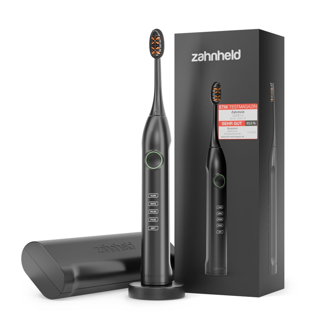 Schwarze elektrische Zahnbürste mit Etui, Ladestation und Verpackung. Zahnheld Logo und Testmagazin-Auszeichnung sichtbar.