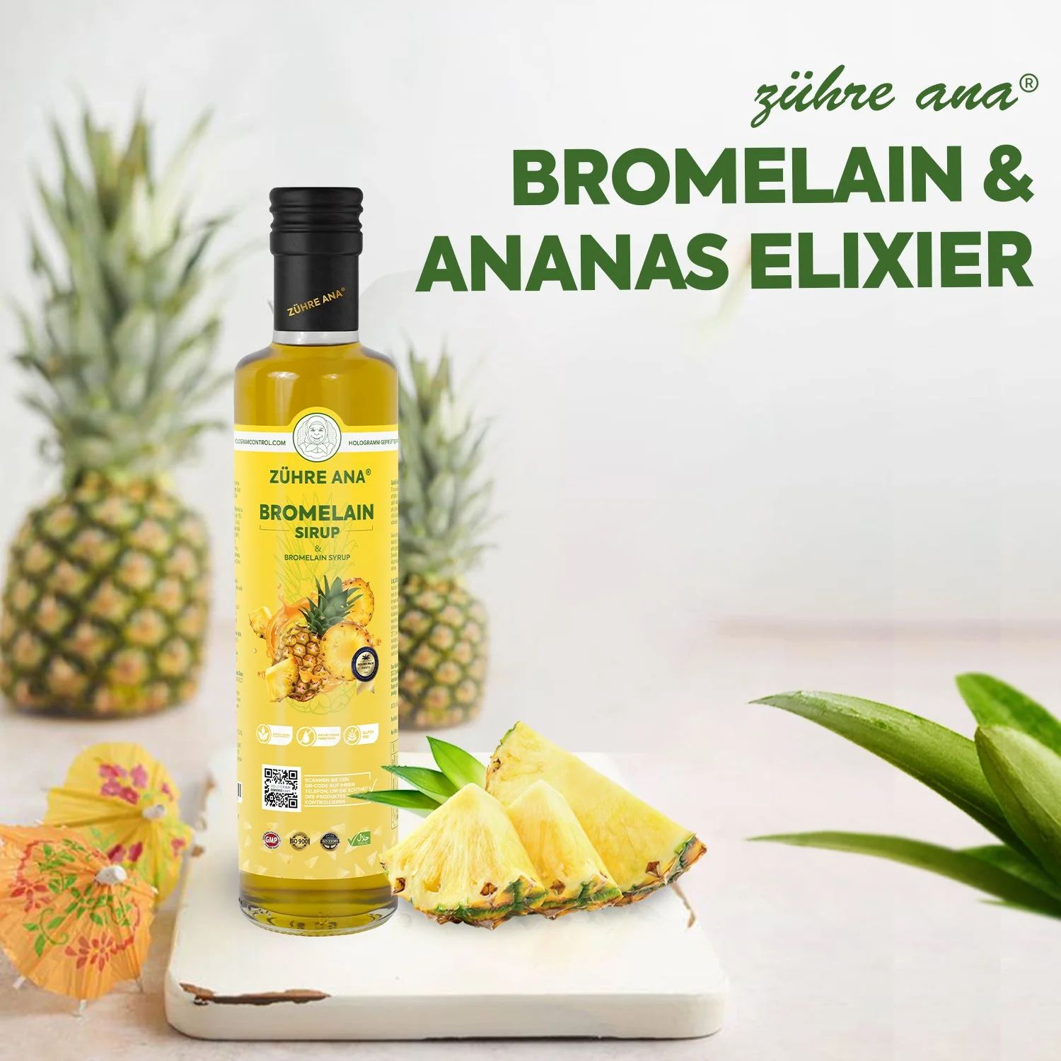 Gelbe Flasche mit schwarzem Deckel. Aufschrift: Zühre Ana Bromelain Sirup. Ananas und Ananasstücke daneben.