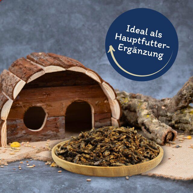 Getrocknete Heimchen in einer Holzschale. Holzhaus und Ast im Hintergrund. Text: Ideal als Hauptfutterergänzung.