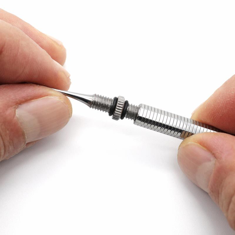Hände halten Zahnstocher mit gerader, abschraubbarer Spitze. Metall. Schwarzer Ring am Gewinde.