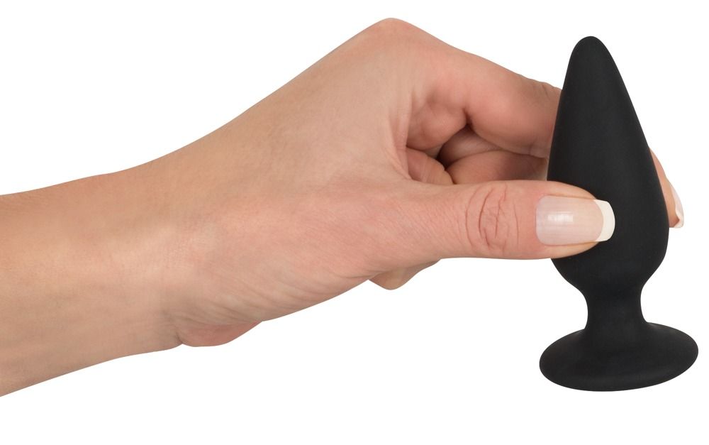 Schwarzer Analplug mit Standfuß, gehalten von einer Hand. Kegelförmiger Aufsatz, runder Fuß.