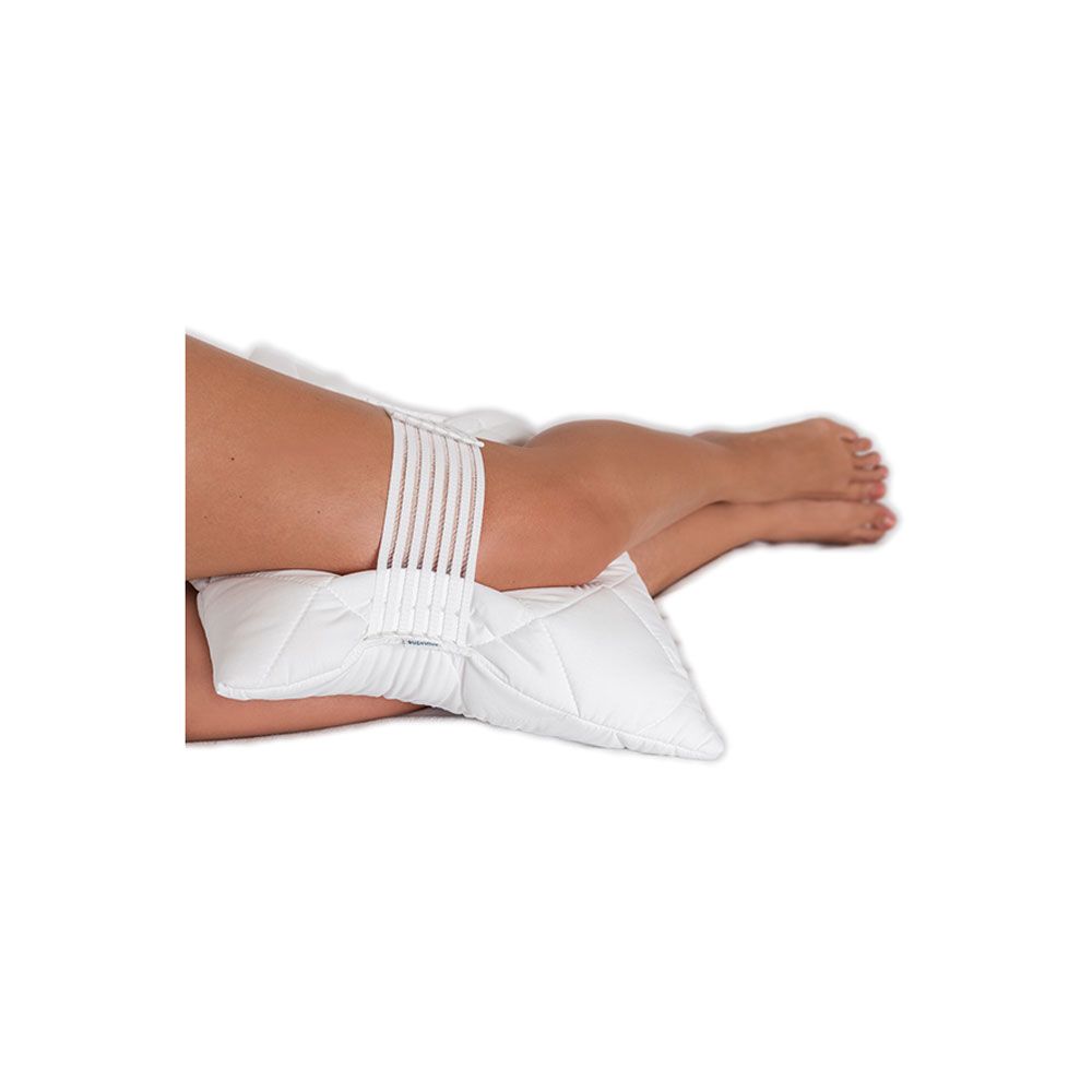 Weißes Kniekissen mit Gurtband an einem Bein. Die Person liegt auf der Seite. Das Kissen ist unter dem Knie platziert.
