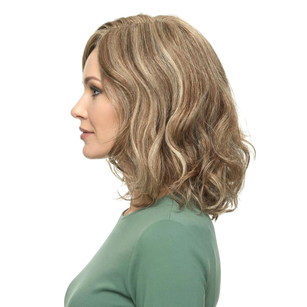 Perücke mit gewelltem, blond-braunem Haar. Seitenansicht einer Frau mit grünem Oberteil.