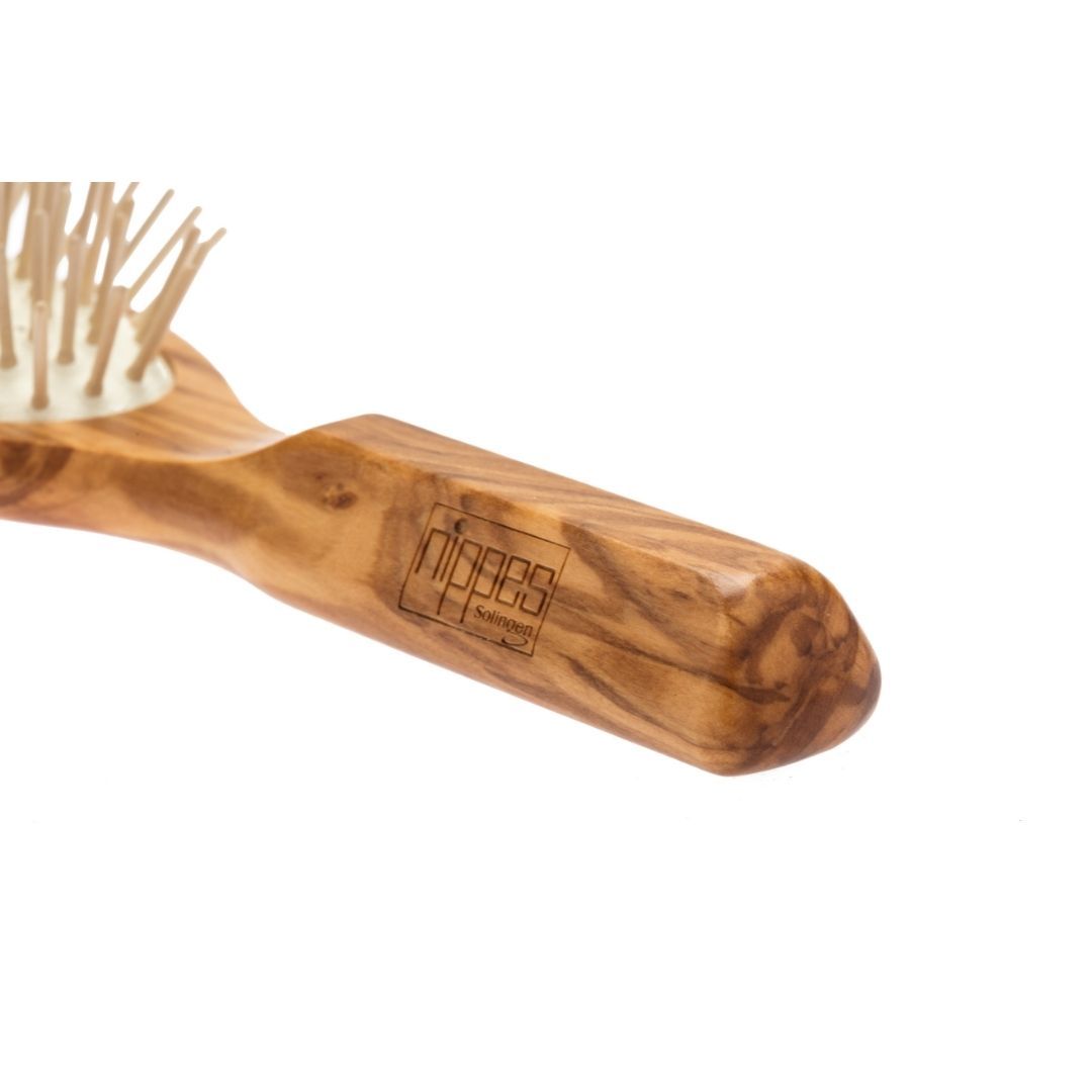 Bürste aus Olivenholz mit Holzstiften. Griff mit Logo. Nahaufnahme.