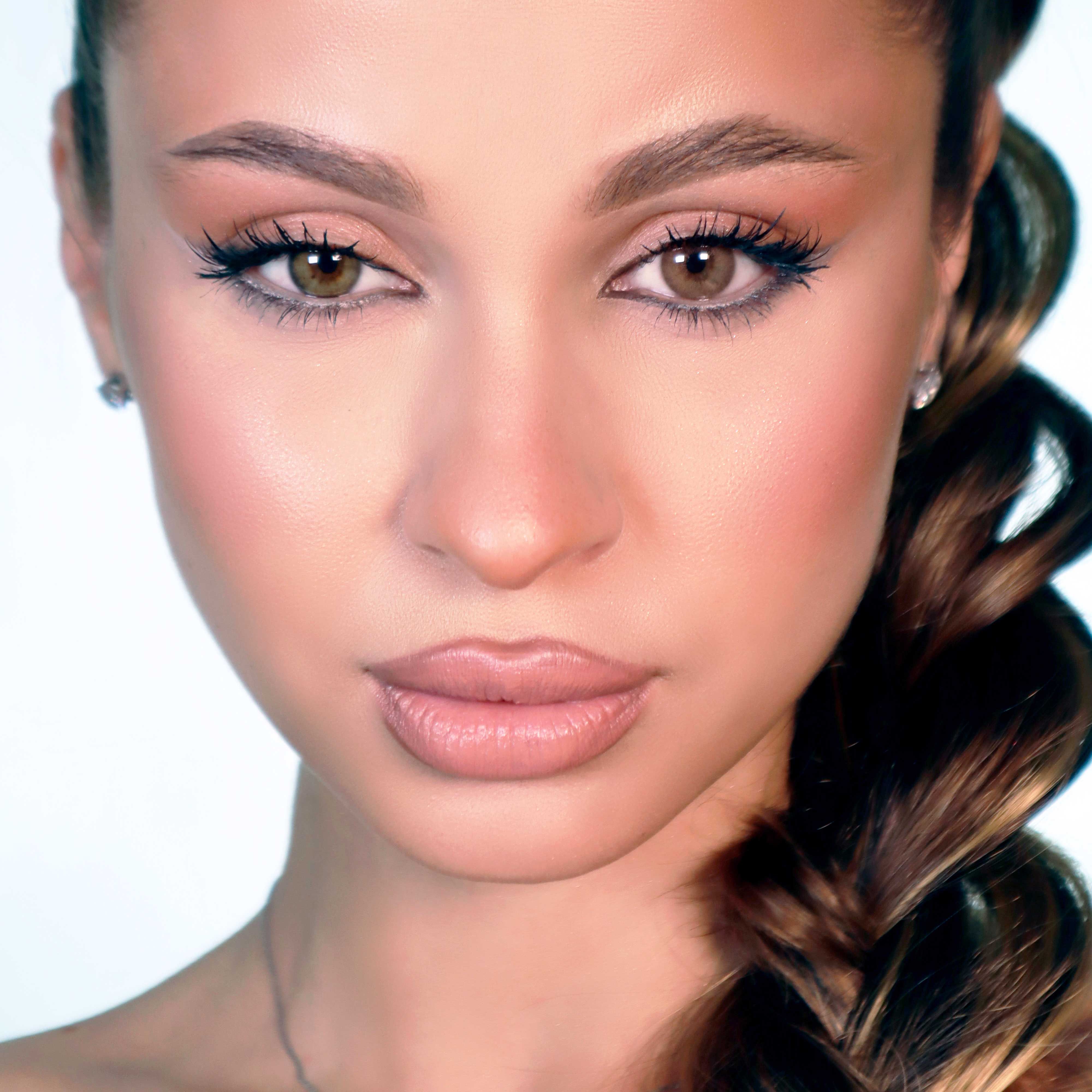 Porträt einer Frau mit braunen Augen. Sie trägt Kontaktlinsen. Geflochtene Frisur. Deutliches Make-up.