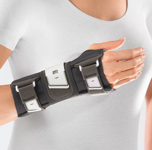 Nahaufnahme der L&R Cellacare Manu Control Comfort Handgelenkorthese am Handgelenk. Graue Farbe mit weißen Verschlüssen.
